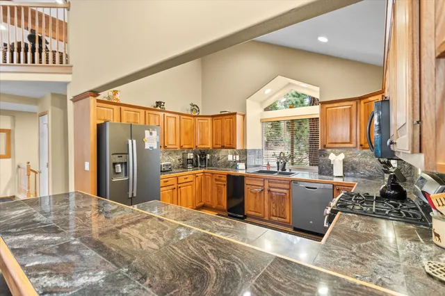 a large kitchen with stainless steel appliances granite countertop a stove a sink dishwasher and a refrigerator with wooden floor