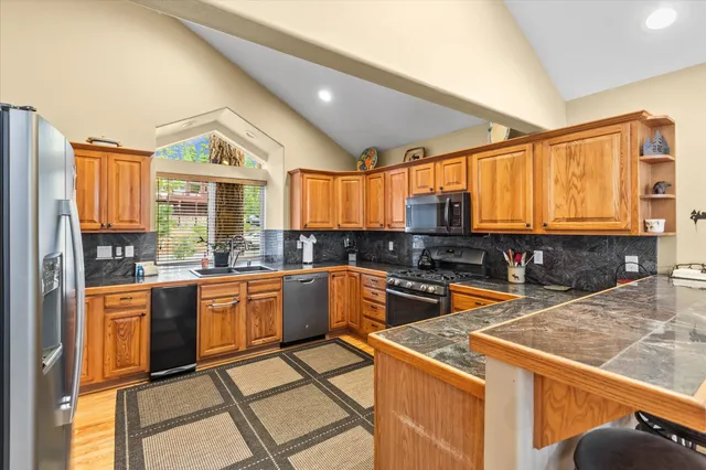 a kitchen with stainless steel appliances granite countertop a stove a sink and a microwave