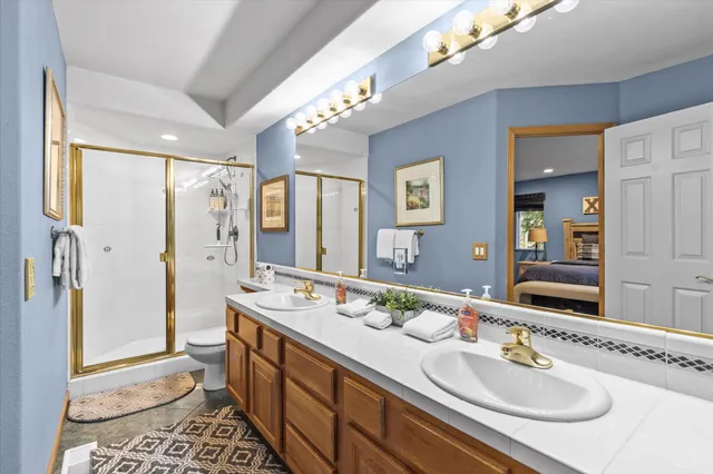 a bathroom with a sink double vanity granite tub shower and a mirror