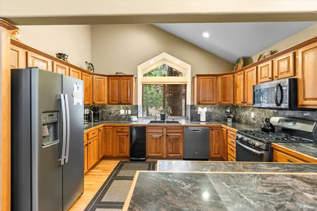 a kitchen with stainless steel appliances granite countertop a refrigerator a stove top oven a sink and dishwasher