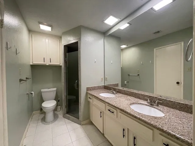 a bathroom with a granite countertop sink a toilet a large mirror and a shower