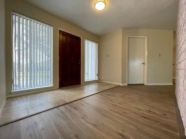 a view of an empty room with wooden floor and a window