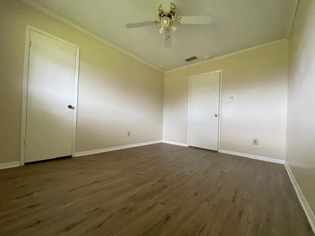 an empty room with wooden floor and fan chandelier