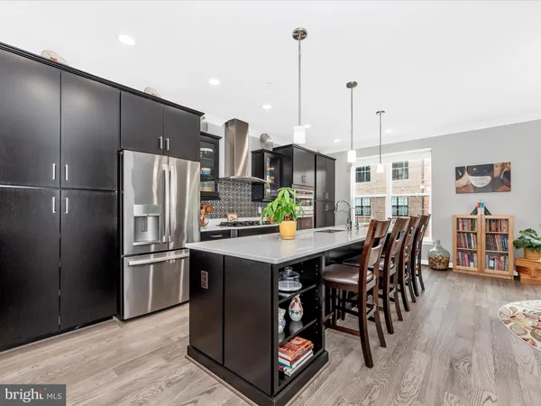 a kitchen with stainless steel appliances granite countertop a refrigerator a stove a sink a dining table and chairs