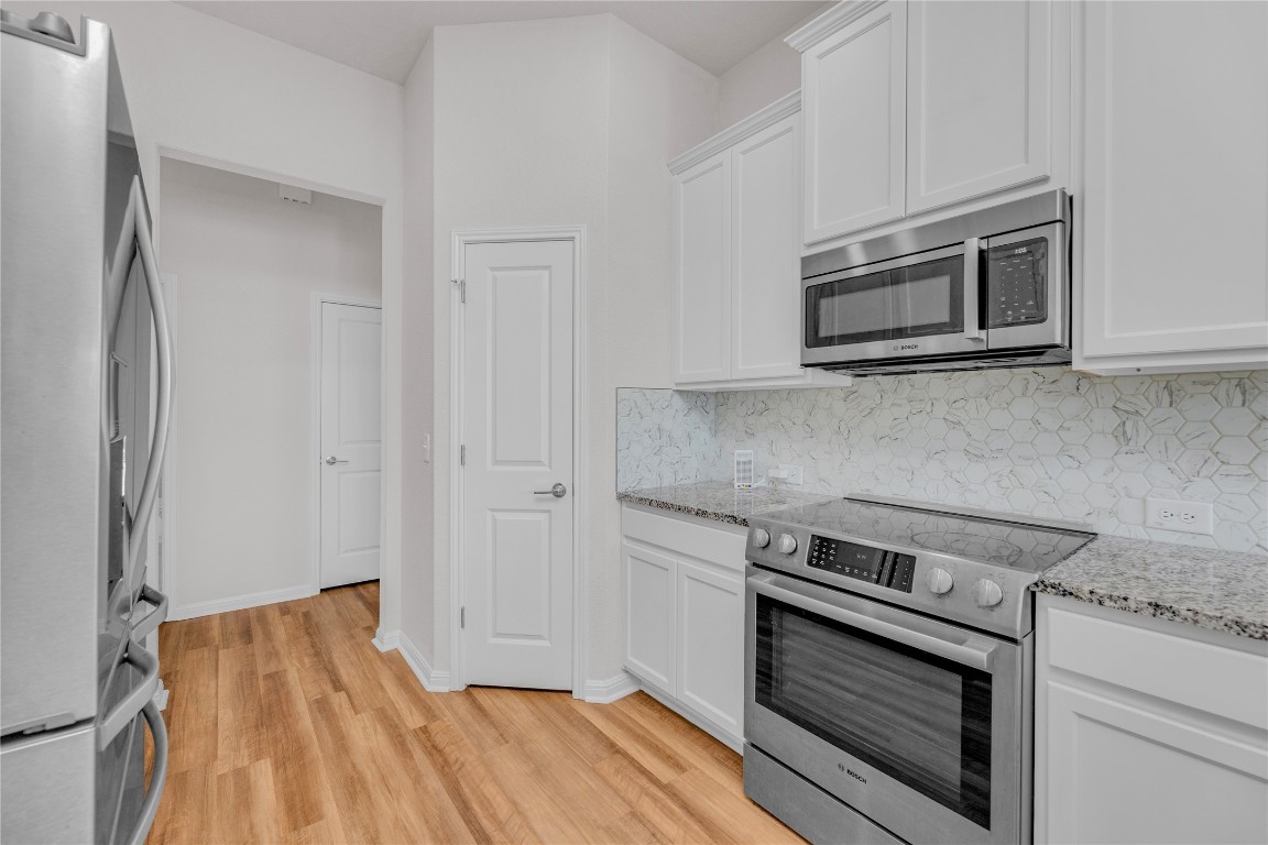 9941 Comely Bend Manor, TX 78653 - Photo 8 of 31 a kitchen with granite countertop wooden cabinets and stainless steel appliances
