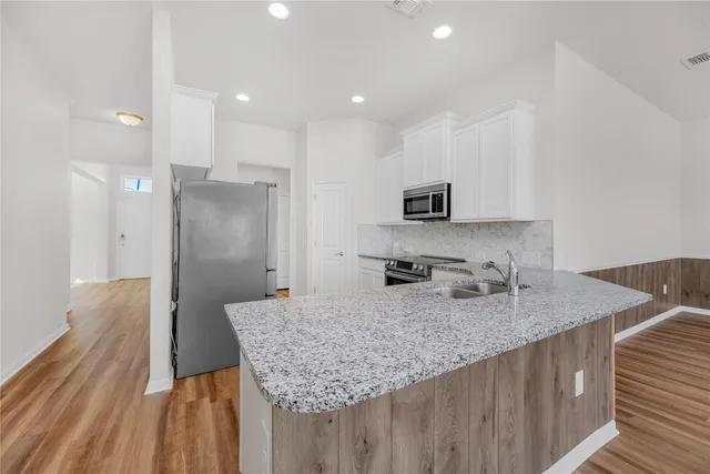 a kitchen with granite countertop kitchen island sink refrigerator and microwave
