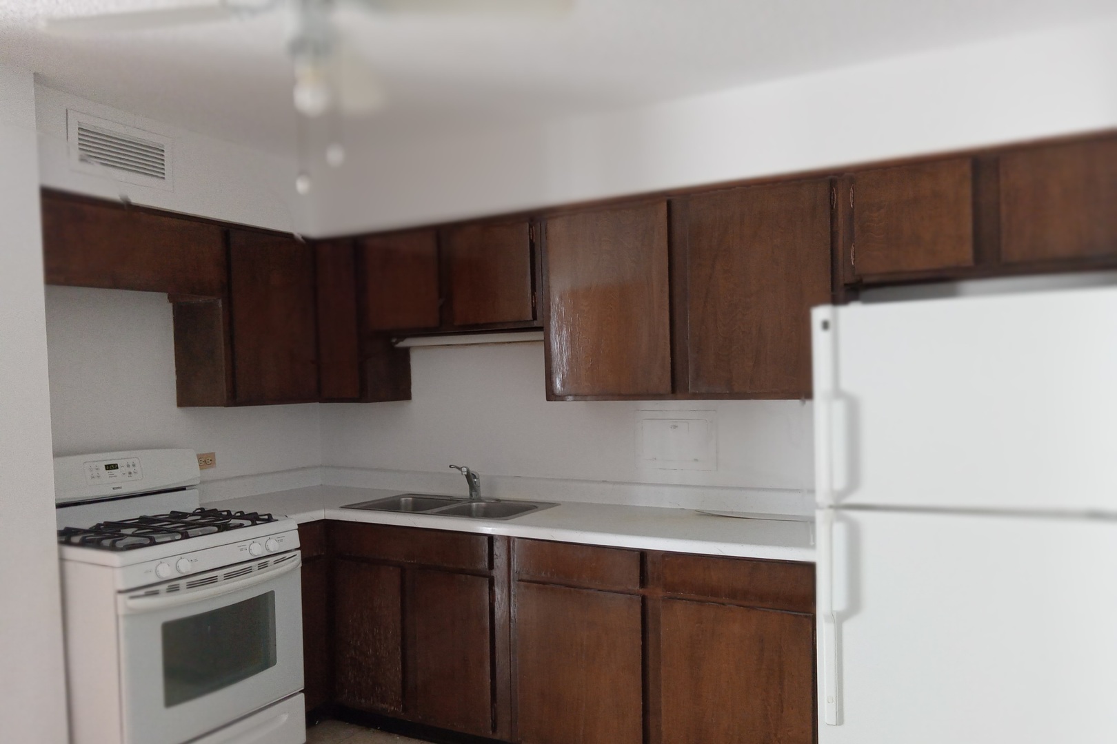 8809 Golf Road, Unit 10C Niles, IL 60714 - Photo 5 of 6 a kitchen with wooden cabinets and white stainless steel appliances
