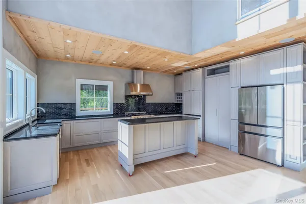 a kitchen with stainless steel appliances kitchen island granite countertop a refrigerator and a stove top oven