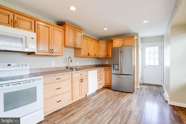 a kitchen with a refrigerator a stove top oven and wooden floors