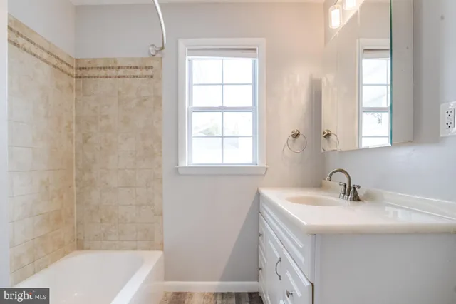 a bathroom with a sink a bathtub and a window