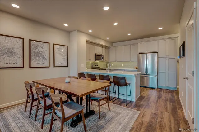 a kitchen with stainless steel appliances granite countertop a dining table chairs refrigerator sink and cabinets
