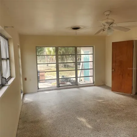 a view of an empty room with a window and a kitchen