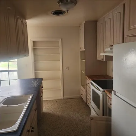 a kitchen with granite countertop a sink a stove and refrigerator