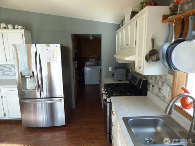 a kitchen with stainless steel appliances granite countertop a refrigerator a stove and a sink with wooden floor