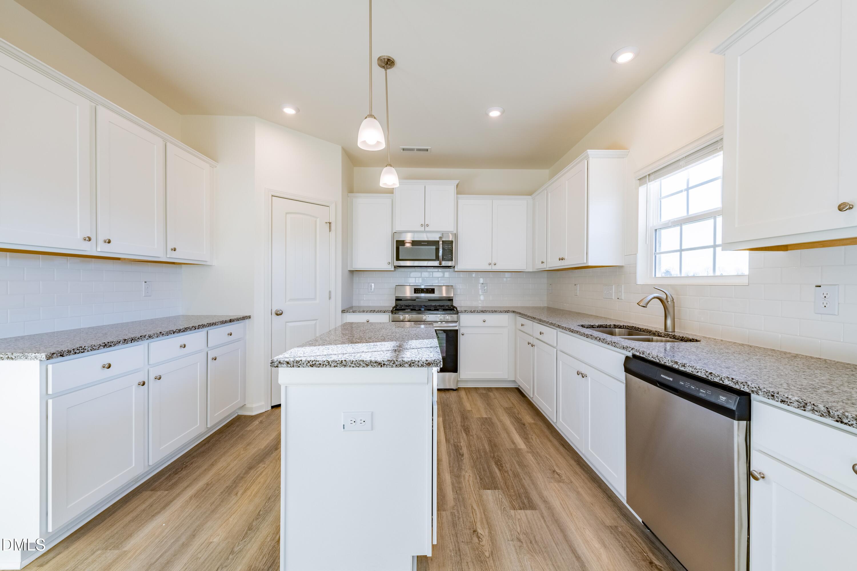 55 Fern Ridge Drive, Unit 1 Cameron, NC 28326 - Photo 12 of 42 a kitchen with granite countertop white cabinets sink and stainless steel appliances