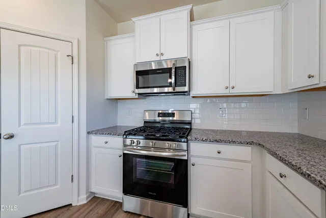 a kitchen with stainless steel appliances granite countertop grey cabinets and a stove top oven