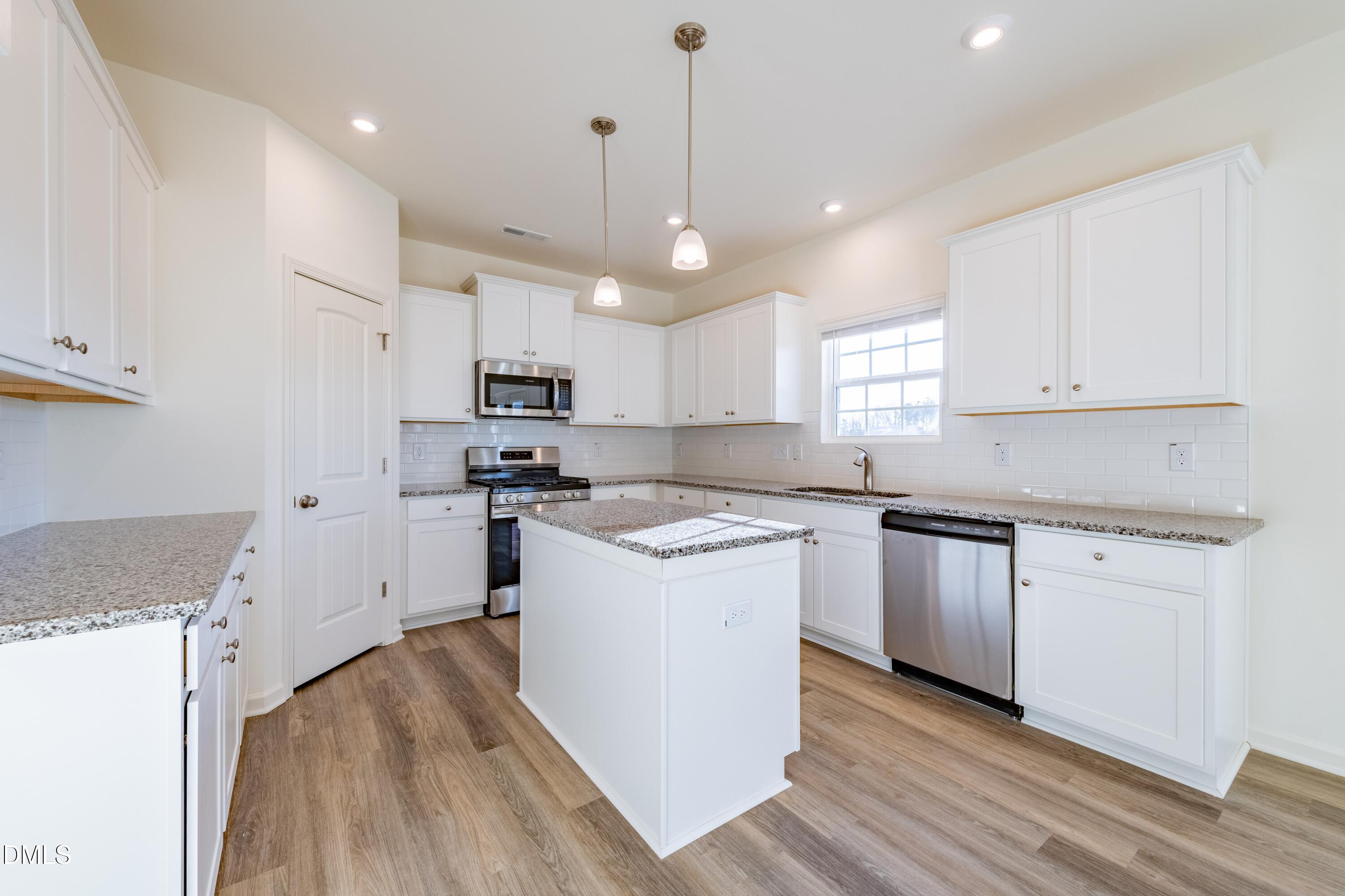55 Fern Ridge Drive, Unit 1 Cameron, NC 28326 - Photo 16 of 42 a kitchen with granite countertop a refrigerator a sink dishwasher a stove and white cabinets with wooden floor