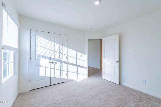 an empty room with windows and chandelier fan