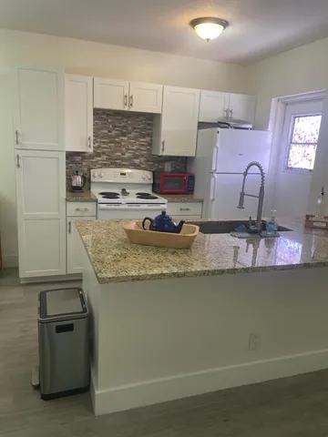 a kitchen with kitchen island granite countertop a sink cabinets and stainless steel appliances