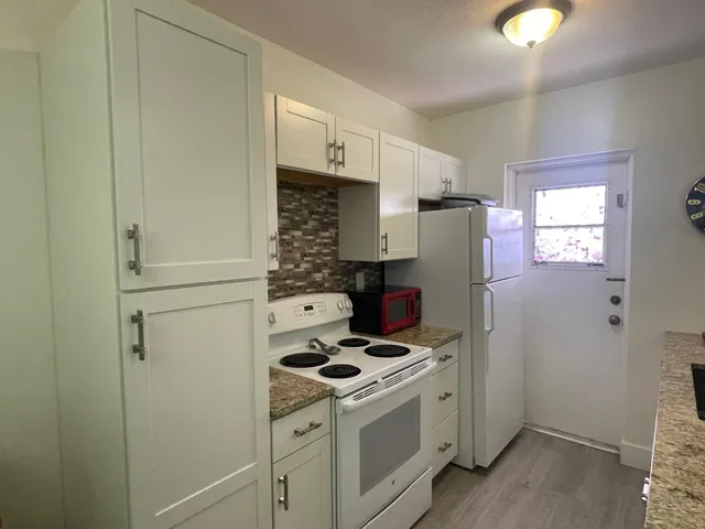 a kitchen with granite countertop a sink a stove and a wooden floor