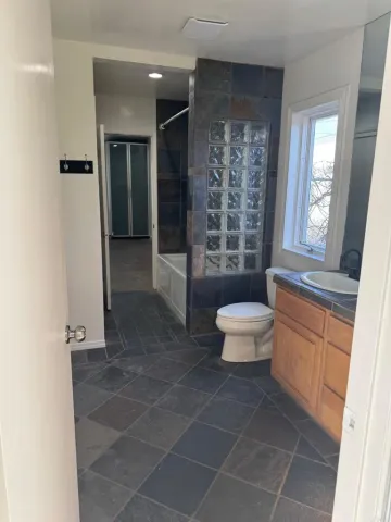 a bathroom with a granite countertop sink a toilet a mirror and shower
