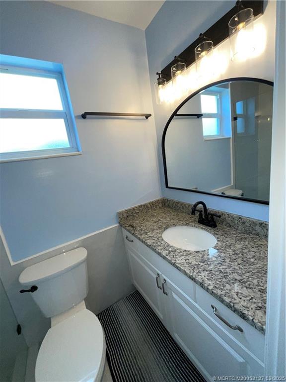 661 Hernando Street, Unit 6 Fort Pierce, FL 34949 - Photo 11 of 12 a bathroom with a granite countertop toilet sink and mirror