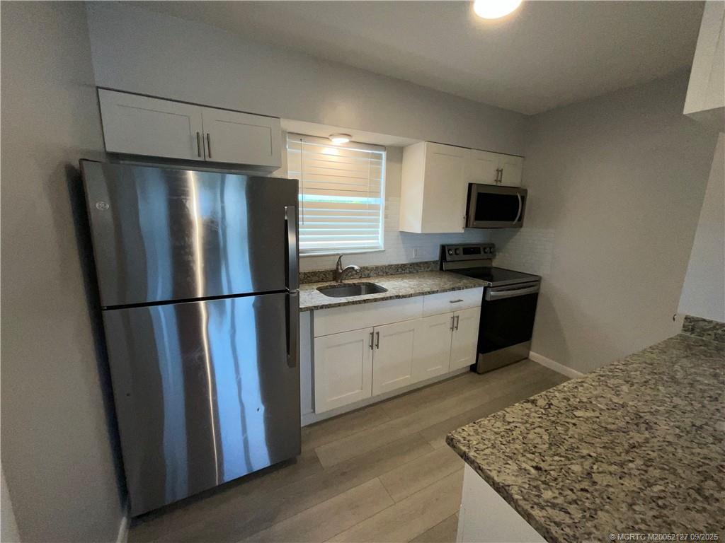661 Hernando Street, Unit 6 Fort Pierce, FL 34949 - Photo 5 of 12 a kitchen with a refrigerator and a stove top oven