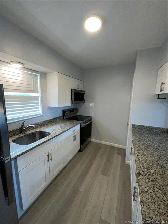 661 Hernando Street, Unit 6 Fort Pierce, FL 34949 - Photo 6 of 12 a kitchen that has a sink a stove and cabinets