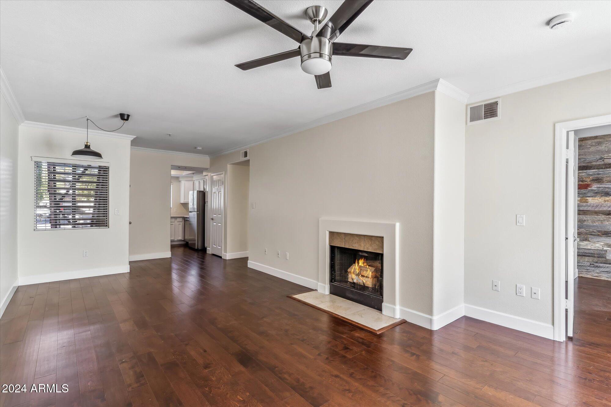 a view of an empty room with wooden floor a fireplace and a window