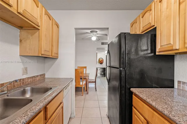 a kitchen with stainless steel appliances granite countertop a sink a refrigerator and a wooden cabinets