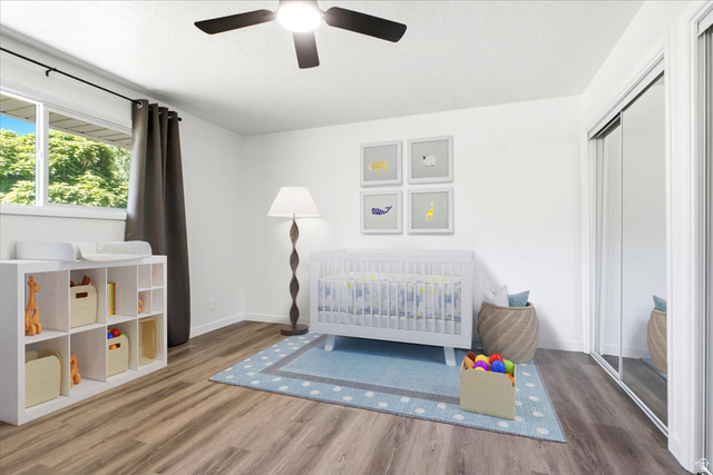 1676 East 11245 South Sandy, UT 84092 - Photo 17 of 34 Bright room featuring wood-finish flooring, a ceiling fan with integrated lighting, a window with exterior tree views, and mirrored sliding closet doors. This photo is virtually staged
