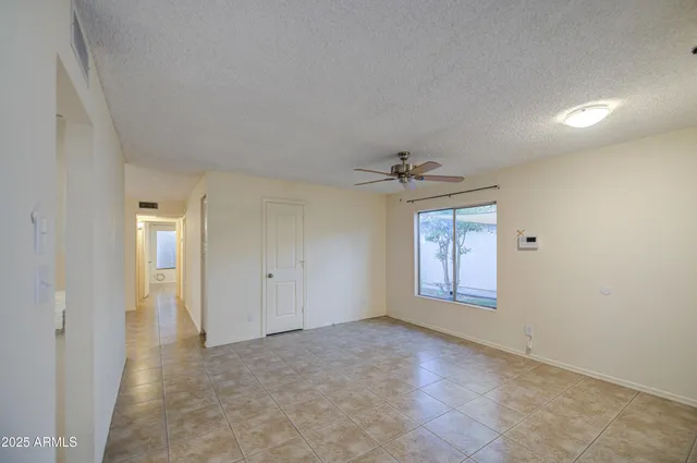 en empty room with ceiling fan and window