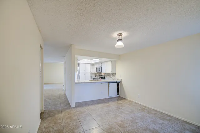 an empty room with chandelier fan and windows