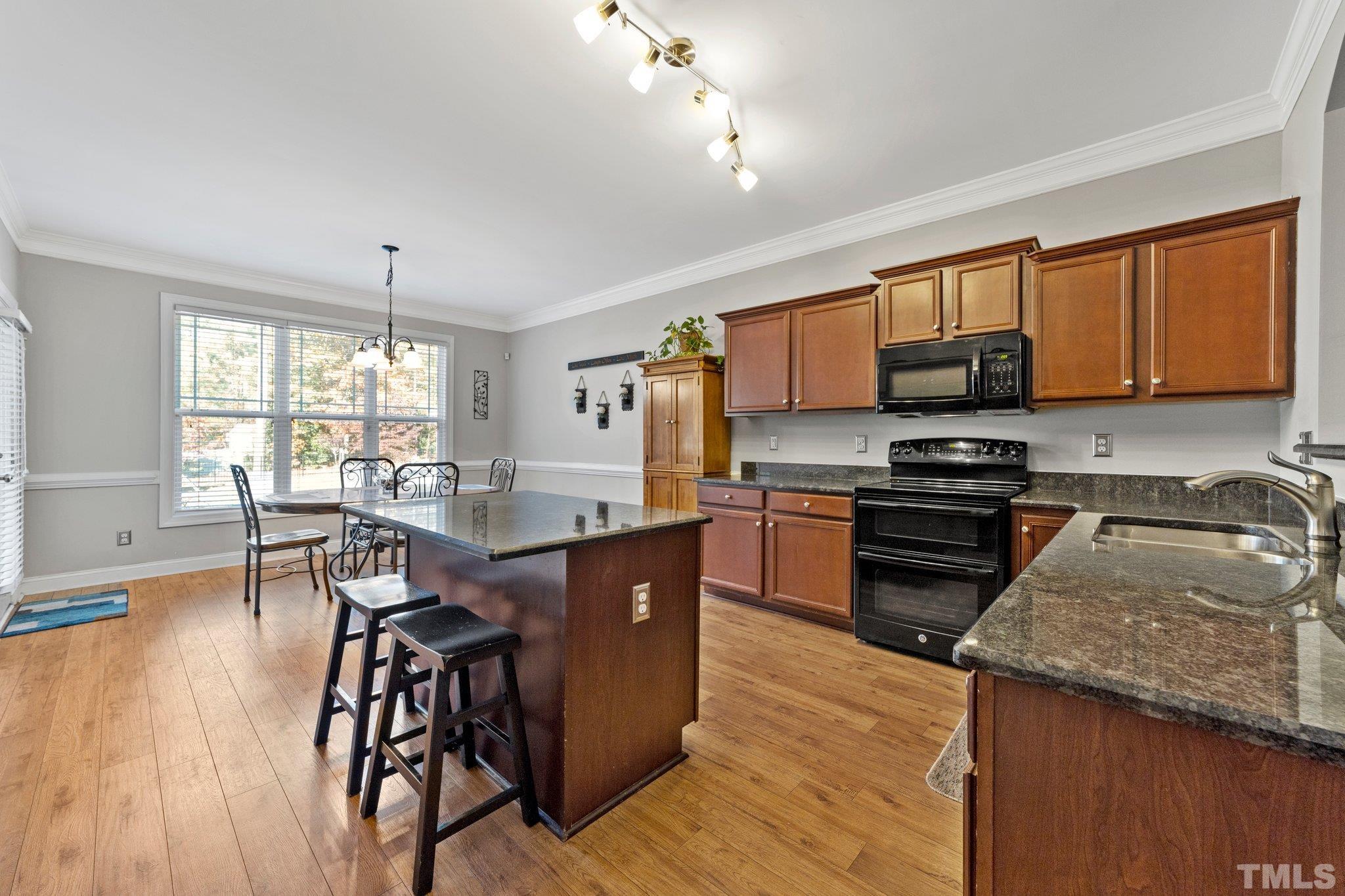 270 Timberland Drive Angier, NC 27501 - Photo 6 of 30 a kitchen with stainless steel appliances granite countertop wooden floors stove top oven with a dining table and chairs