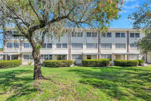a view of a house next to a big yard and large trees