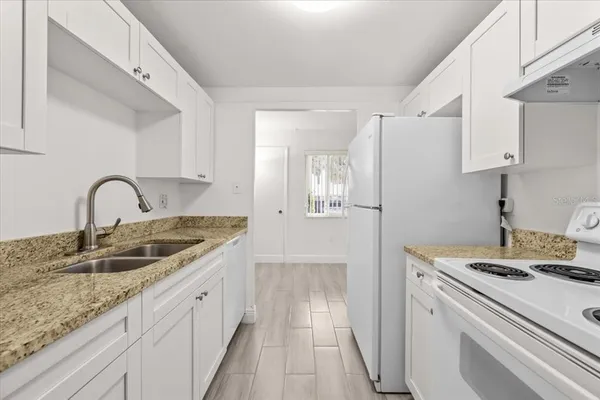 a kitchen with granite countertop a sink stove and refrigerator
