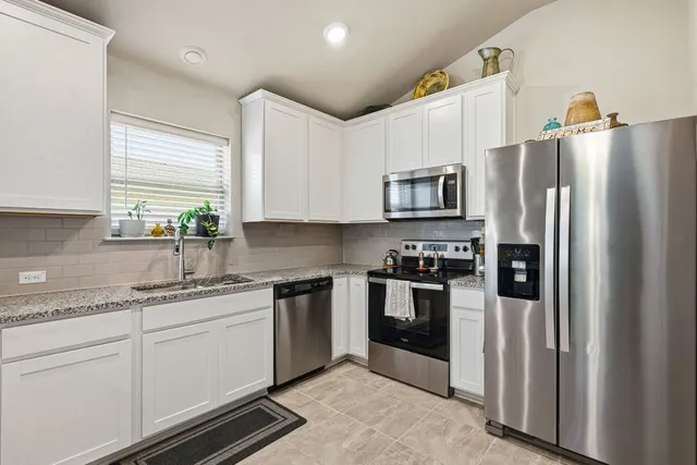 a kitchen with stainless steel appliances granite countertop a refrigerator sink and stove