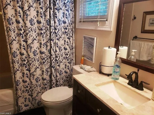 a bathroom with a granite countertop sink and a toilet