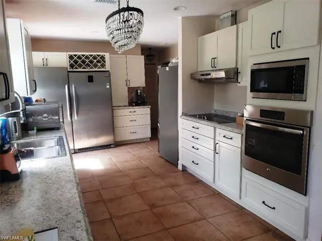 a kitchen with stainless steel appliances kitchen island granite countertop a stove a refrigerator and a sink