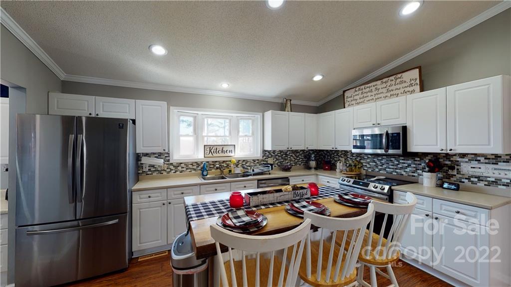 2130 Peeler Road Vale, NC 28168 - Photo 9 of 29 a kitchen with stainless steel appliances kitchen island granite countertop a refrigerator a stove a sink dishwasher a dining table and chairs with wooden floor