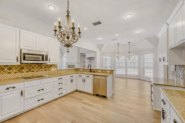 a kitchen with granite countertop white cabinets and stainless steel appliances