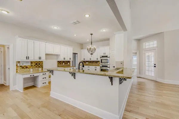 a large white kitchen with stainless steel appliances