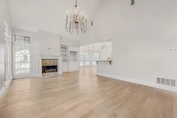 a view of a livingroom with a fireplace a chandelier and windows