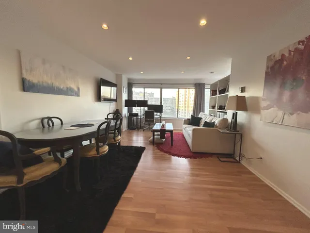 a living room with furniture kitchen view and a wooden floor