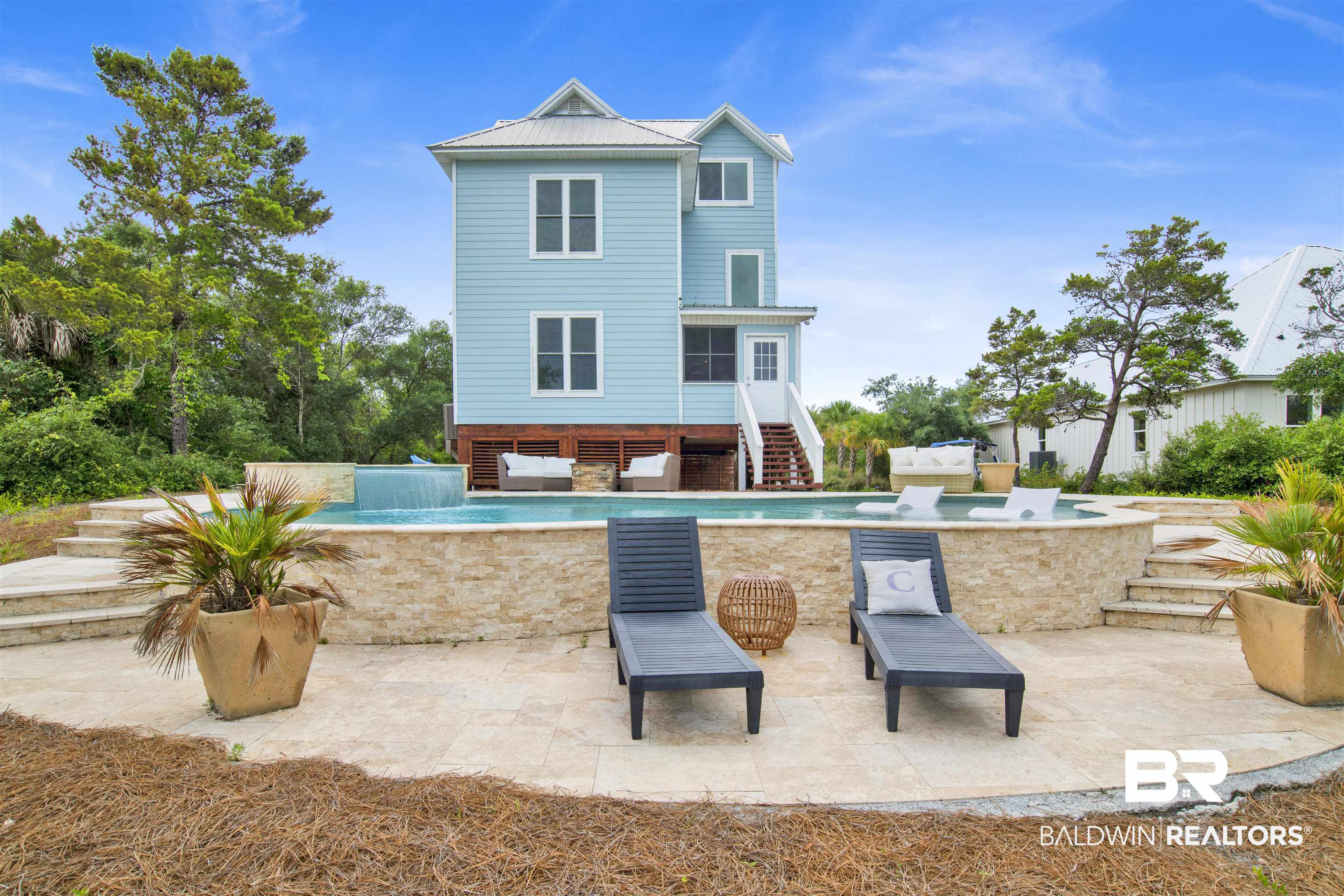 30351 River Road Orange Beach, AL 36561 - Photo 29 of 44 Light blue siding exterior featuring multiple windows and a metal roof