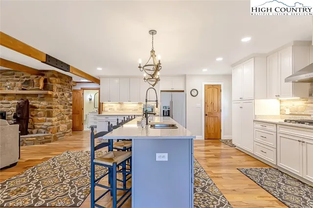 a open kitchen with stainless steel appliances granite countertop a stove a refrigerator a oven a dining table and chairs with wooden floor