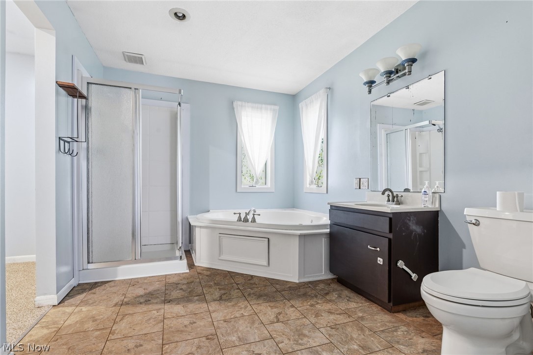 4449 18th Street Northwest Canton, OH 44708 - Photo 14 of 25 Bathroom featuring a built-in corner soaking tub, a stand-up shower with sliding glass doors, and a single vanity with storage
