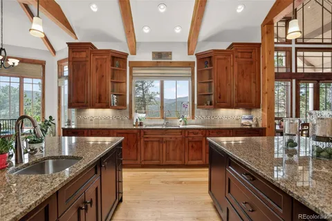 a kitchen with stainless steel appliances granite countertop a sink a stove and a wooden cabinets
