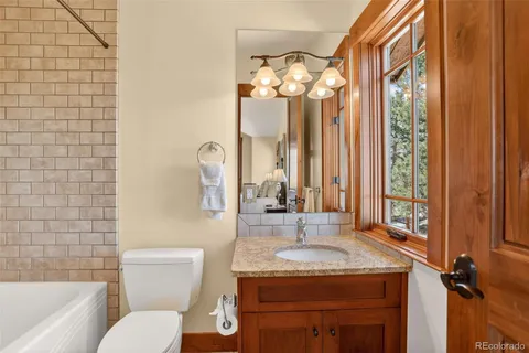 a bathroom with a granite countertop sink toilet a mirror and shower
