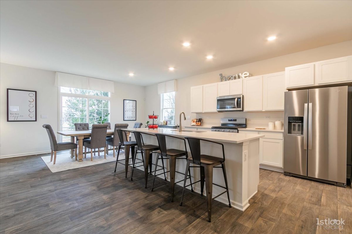 10453 Privet Drive St. John, IN 46307 - Photo 4 of 37 a kitchen with kitchen island granite countertop stainless steel appliances a dining table and chairs